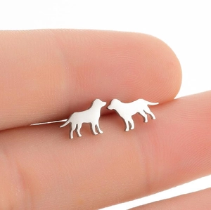 Polished silver dog silhouette stud earrings shown on finger for scale reference