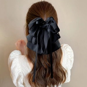 Detail of a large black layered chiffon bow hair claw clip with long ribbons on hair