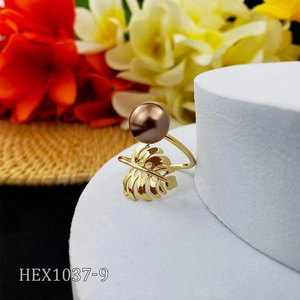 Detail of gold monstera leaf ring with brown pearl on white display stand