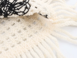 Detailed close-up of cream crochet knit vest featuring fringe hem and floral embroidery
