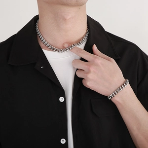 Men's polished silver Cuban link chain necklace and bracelet set worn by a male model