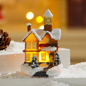 Detail of glowing resin Christmas train station with warm LED lights and snowy roof