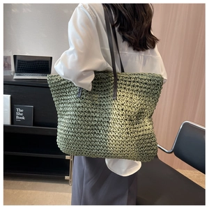 Rear side view of a large green woven tote bag carried by a model in a minimalist room