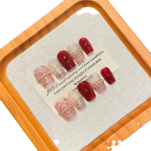 Handgemaakte kunstnagels met rode glitters, nude pailletten en roze parel-ruitpatronen