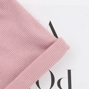 Gros plan du bonnet tricoté rose pour bébé montrant la texture du tissu et le revers plié