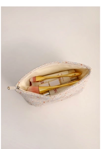 Top view of open tweed cosmetic bag showing spacious interior for skincare products