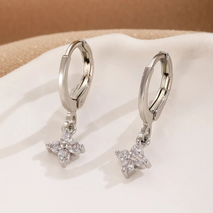 Detailed macro view of silver flower huggie earrings with sparkling zircon inlay