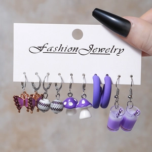 Detailed view of five-pair purple earring set with butterfly and mushroom charms