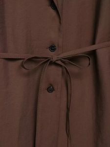 Close-up of dark brown woven blazer fabric with black button and adjustable waist tie
