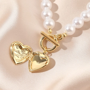 Macro detail of open gold heart locket showing 'I love you' engraving and pearls