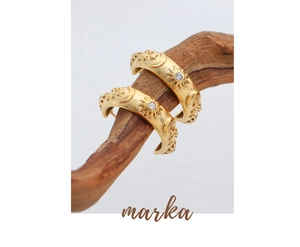 Macro detail of gold earrings with sun, moon and star motifs on a wooden branch
