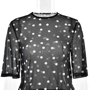 Detail of sheer black mesh fabric with white polka dots on a short-sleeved top