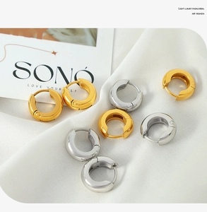 Macro detail of polished gold and silver hoop earrings on elegant white draped fabric