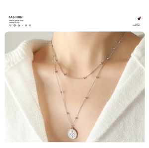 Detail of silver double layer necklace featuring beaded chain and evil eye coin pendant