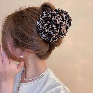 Pince à cheveux fleur en tissu imprimé léopard portée par un mannequin sur un chignon