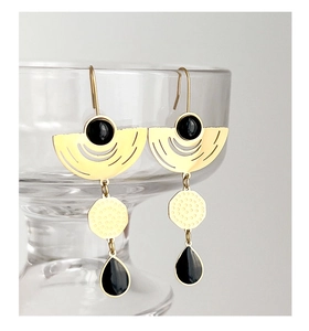 Detail of gold geometric earrings with black crystal drops on a clear glass edge