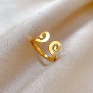 Detailed close-up of a golden spiral ring with cloud patterns on beige silk background