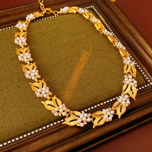 Detail of vintage gold flower necklace featuring white pearls and zircon in a wood frame