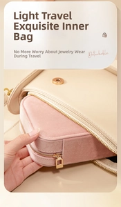 Pink velvet jewelry organizer being placed into a leather handbag for travel portability