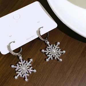 S925 silver snowflake earrings with zirconia and white pearls on a dark wood background