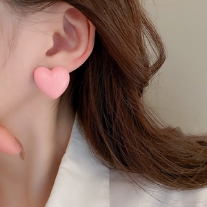Close-up of pink 3D heart-shaped earring worn on earlobe for a chic feminine style