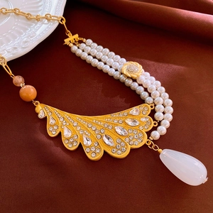 Macro detail of luxury multi-layer pearl necklace with gold fan pendant and crystal accents