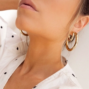 Polished gold-plated C-shaped chunky hoop earrings on female model for a modern minimalist look