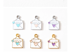 Macro detail of alloy envelope heart charms in assorted enamel colors and metallic finishes