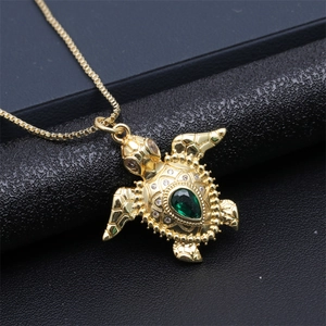 Macro view of gold turtle pendant with green pear-shaped gemstone and white crystals