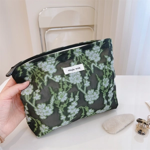 Close-up of semi-transparent black mesh pouch with green floral patterns and simple wish tag