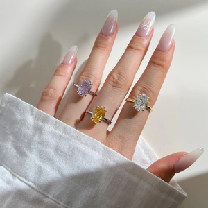 Detailed view of three oval-cut zircon rings in pink, yellow, and white on a model's hand