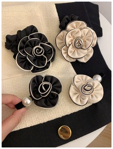 Detail of camellia hair ties and pearl clips on tweed fabric background in French style