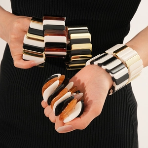 Close-up of geometric stretch bracelets in black, white, and amber acrylic mix on wrist