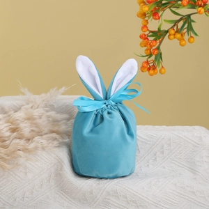 Blue velvet Easter bunny ear pouch with ribbon bow on a textured white blanket