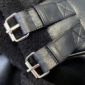 Details des Kunstfellfutters und der Lederbündchen mit Silberschnallen an einer schwarzen Jacke