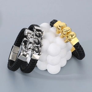 Détail de bracelets en cuir tressé punk avec fermoir ancre argentée et perles crâne dorées