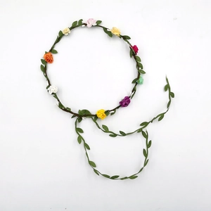 Macro detail of multicolored fabric flowers and green leaves on a vine bridal headband
