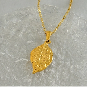 Détail d'un pendentif feuille en or 18k avec motifs de pièces sur pierre bleue