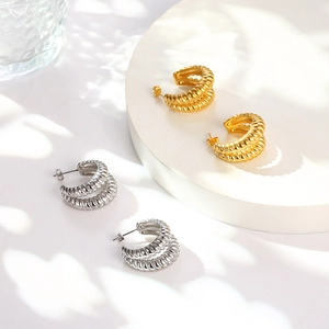 Macro detail of geometric C-shaped stainless steel earrings with spiral ripple textures