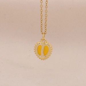 Close-up van gouden ketting met een unieke hartvormige hanger met gele emaille vulling