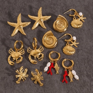 Macro detail of gold titanium steel ocean earrings with pearls and red coral accents