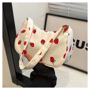 Close-up of white canvas hobo bag featuring red strawberry prints and zipper detail