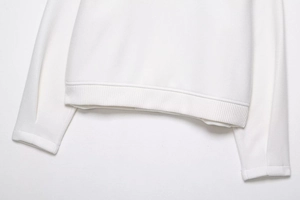 Close-up of ribbed cuffs and hem on a white bomber jacket showing high-quality knit texture