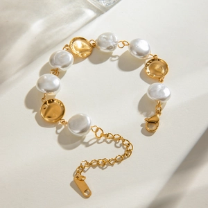 Detail of vintage gold textured discs and white pearls on a stainless steel bracelet