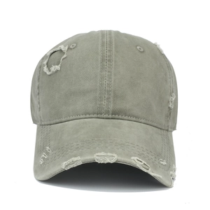 Detail of distressed baseball cap showing washed cotton fabric and decorative torn holes