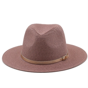 Detailed macro view of woven straw texture and gold faux leather buckle on a pink sun hat