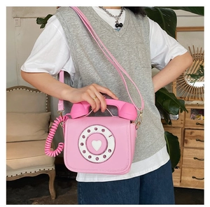 Woman wearing a creative pink retro telephone shaped crossbody bag in a vintage room