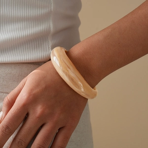 Detail view of wide resin bangle with amber marble texture and high-gloss finish