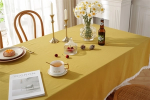 Close-up of yellow cotton tablecloth with white lace edges on a cozy wooden table