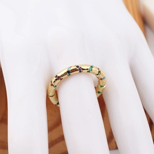 Detail of gold bamboo-shaped ring with colorful inlaid crystals on white hand model
